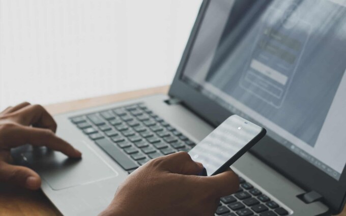 Person using smartphone and laptop for identity management with Okta.