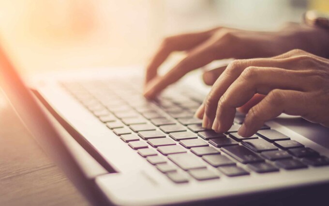 Business professional typing on a laptop keyboard for software integration.