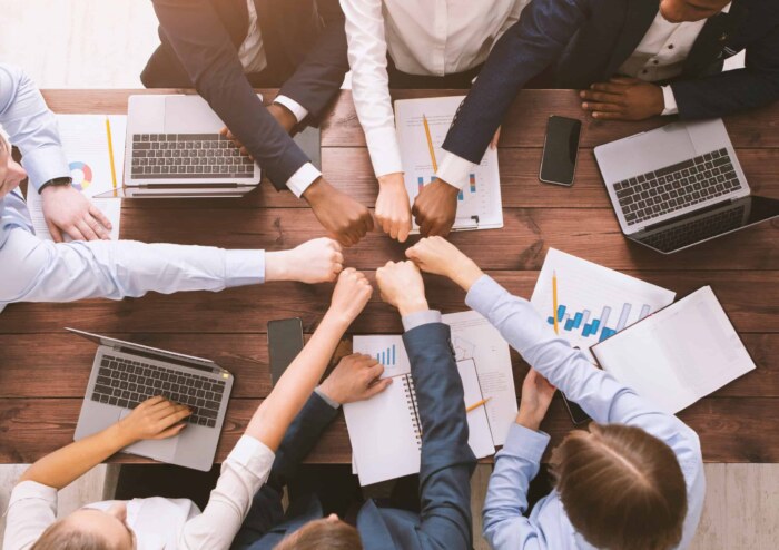 Diverse team members collaborating with fists together for Agile development success.