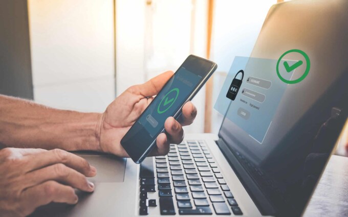 Person authenticating identity using a smartphone and laptop for secure access.