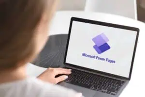 Person using a laptop displaying Microsoft Power Pages logo for website development.