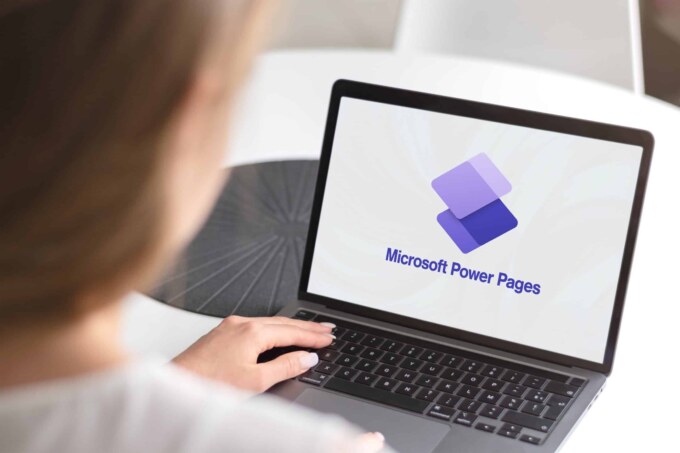 Person using a laptop displaying Microsoft Power Pages logo for website development.
