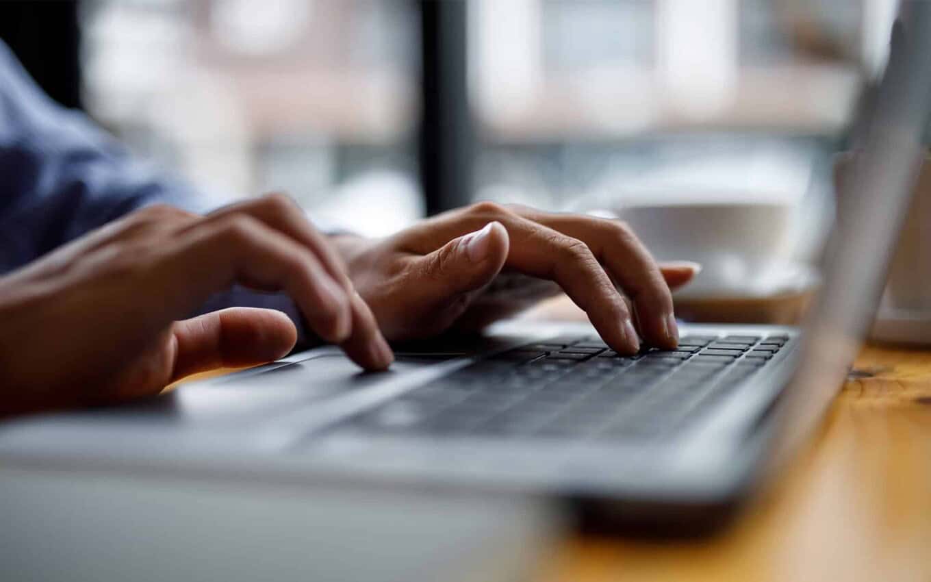 Person typing on a laptop keyboard, representing data migration and database solutions.
