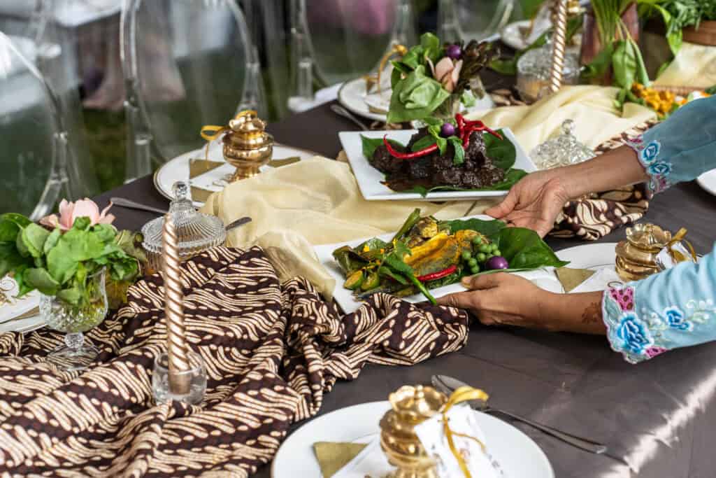 Malay style wedding catering with elegant gold table decorations and candles by idocatering
