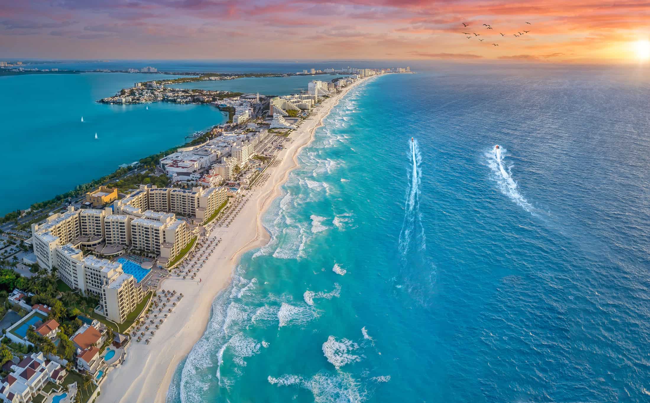 Cancun coast with sun and sailboats