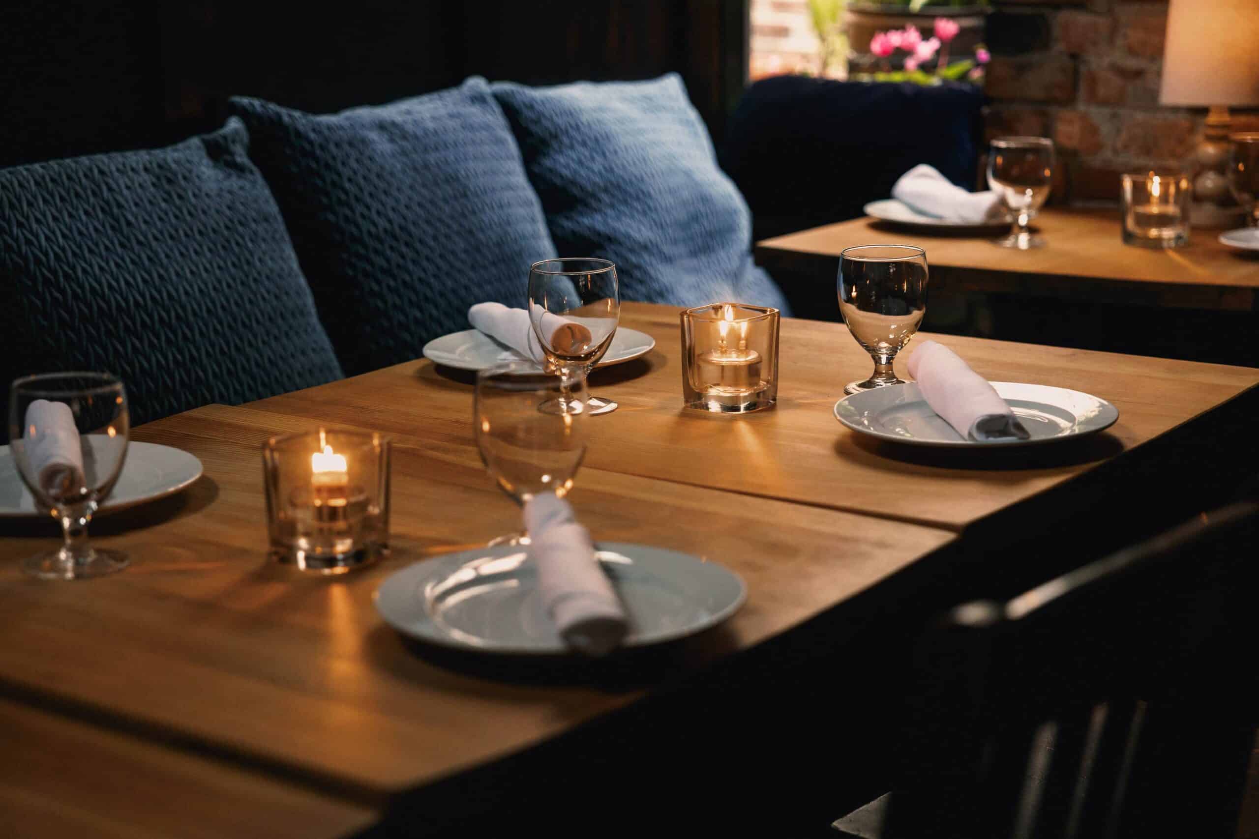 Elegant dining table with candles, glasses, and napkins in a cozy restaurant.