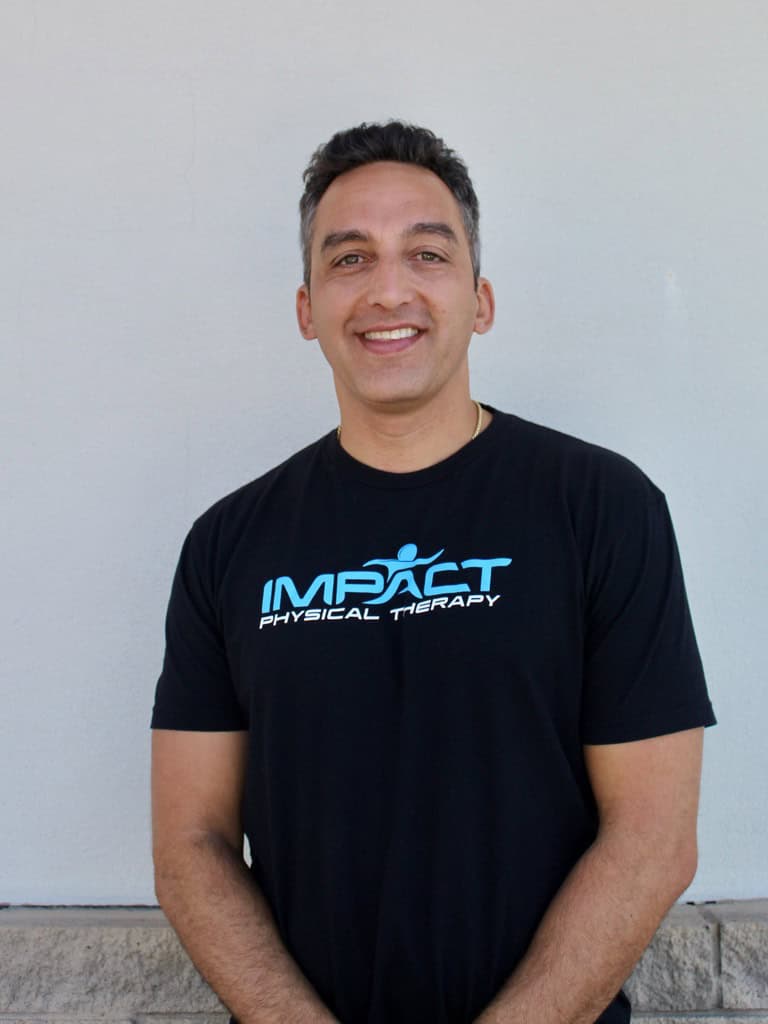 Dr. Eric Hefferon in Impact Physical Therapy shirt smiling outdoors.
