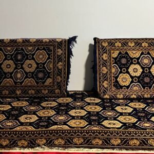 Two cushioned items with black and gold geometric patterns on a matching mat against a white wall.