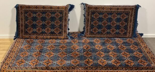 Cushions And Rug With Blue-Orange Geometric Pattern, Fringed Edges, On Wooden Floor.