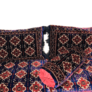 Decorative pillows and bolster with intricate geometric pattern in deep blues, reds, and white accents.
