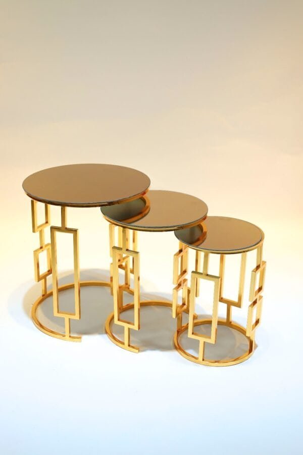 Three Nested Round Tables With Mirrored Tops And Gold Geometric Bases Of Varying Heights.
