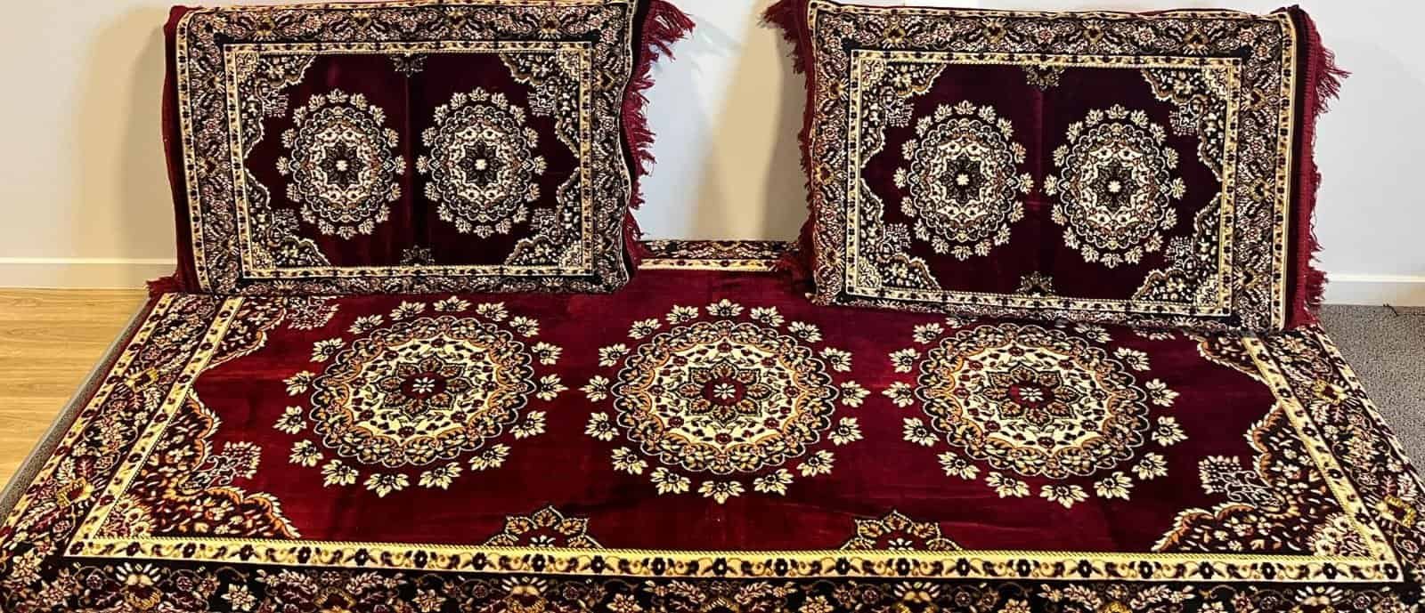Traditional Persian Cushions And Rug With Floral Medallion Designs On Deep Red Background.