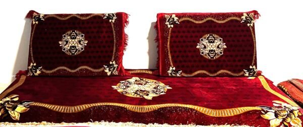 Two Decorative Pillows And A Matching Throw In Red And Gold With Floral Patterns.