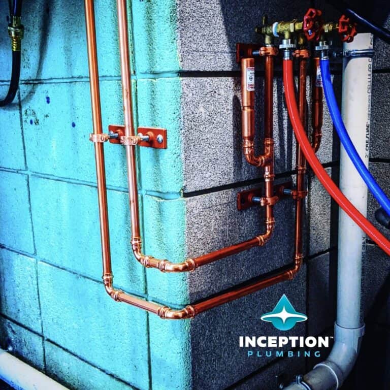 Copper plumbing pipes and fittings are mounted on a concrete wall, with blue and red flexible hoses and a white PVC pipe nearby. Inception Plumbing logo is visible in the bottom right corner.