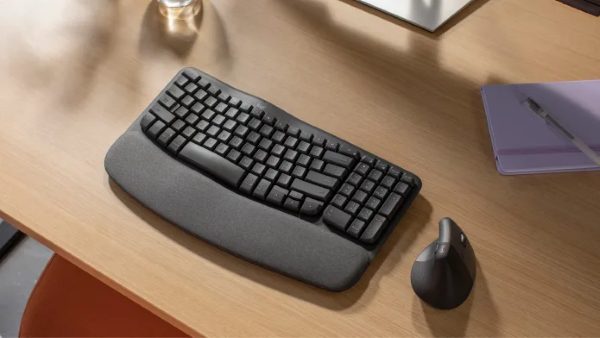 Wireless ergonomic keyboard with wrist support and wireless mouse on wooden office desk, suitable for office productivity and home workspace setup.