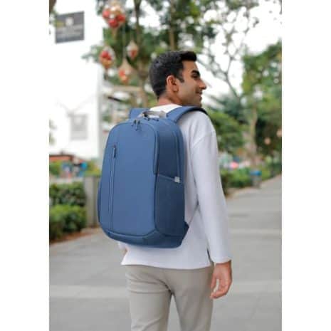 Backpacker with blue laptop bag on city street, modern urban lifestyle, showcasing durable travel gear and innovative backpack designs.