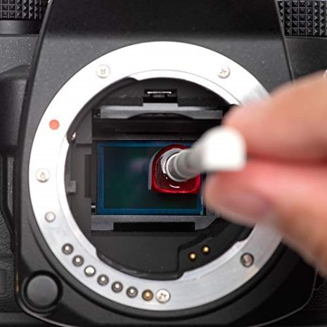 Professional camera maintenance involving cleaning the camera sensor with a cotton swab and cleaning solution to ensure optimal image quality.