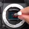 Professional camera maintenance involving cleaning the camera sensor with a cotton swab and cleaning solution to ensure optimal image quality.