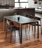 Modern dining table with four chairs in a kitchen setting, with wooden floors and minimalist decor.