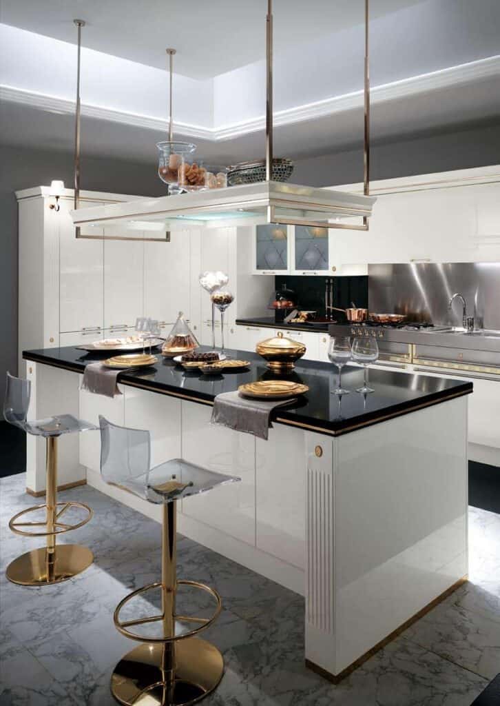 Modern kitchen with white cabinetry, a black countertop, gold accents, transparent bar stools, and elegant decor.
