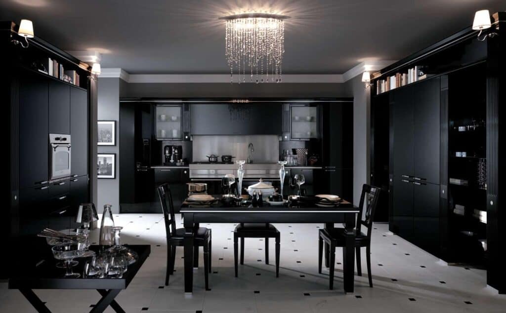 Modern black kitchen and dining area with glossy cabinets, a chandelier, and a set dining table.