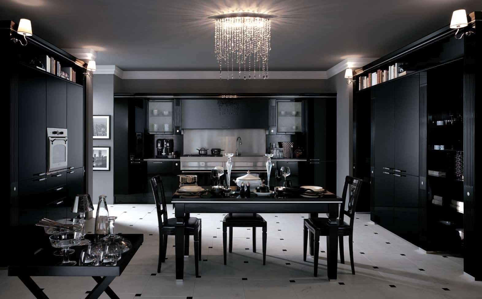Modern black kitchen and dining area with glossy cabinets, a chandelier, and a set dining table.