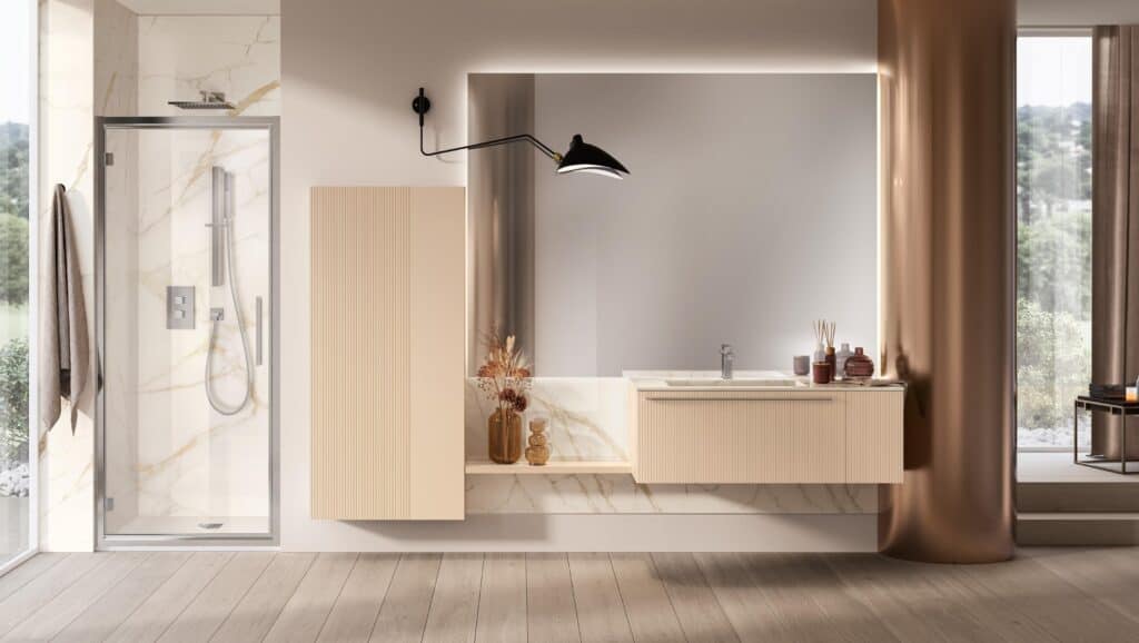 Modern bathroom with a glass shower enclosure, marble wall accents, light wood cabinetry, large mirror with integrated lighting, and a black wall-mounted light fixture.