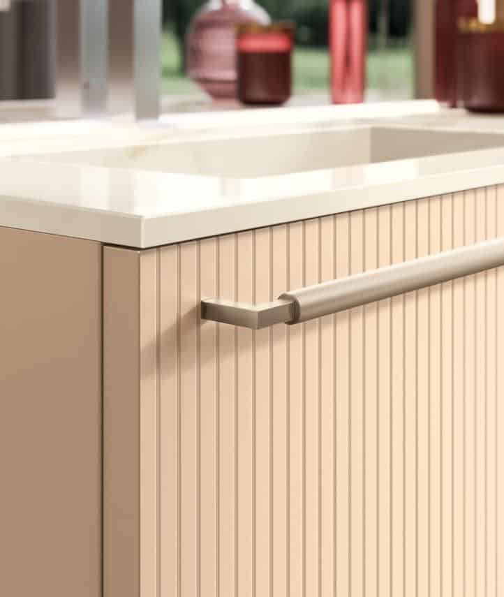 Beige ribbed kitchen cabinet with a sleek metal handle and white countertop.