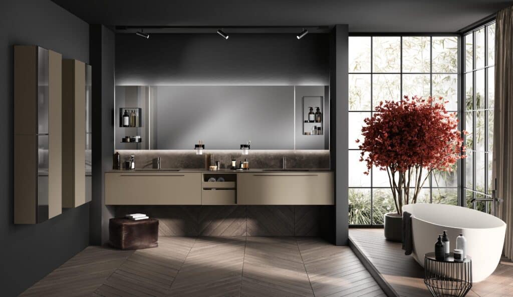 Modern bathroom interior with dual sinks, large mirror, freestanding bathtub, red-leafed indoor tree, and floor-to-ceiling windows.