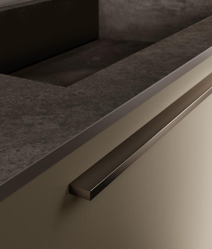 Close-up of a modern kitchen cabinet handle with a dark countertop.