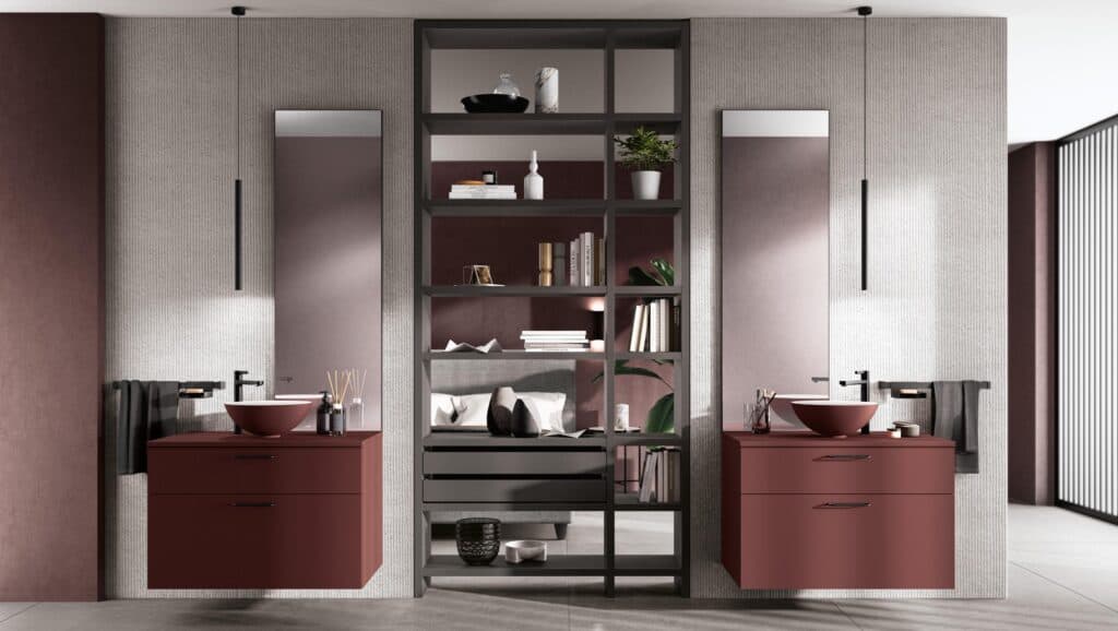Modern bathroom with dual vanities in burgundy, tall mirrors, minimalist shelves with decorative items, and pendant lighting.