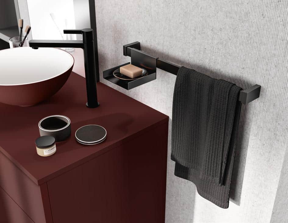 Modern bathroom vanity setup with a maroon countertop, black faucet, round white sink, soap dish, and black towel on a towel bar.