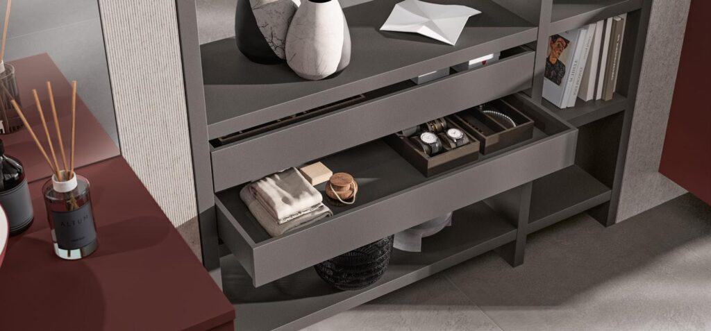 A modern shelving unit with decorative vases, a paper sculpture, books, and neatly arranged accessories like watches and folded clothes.