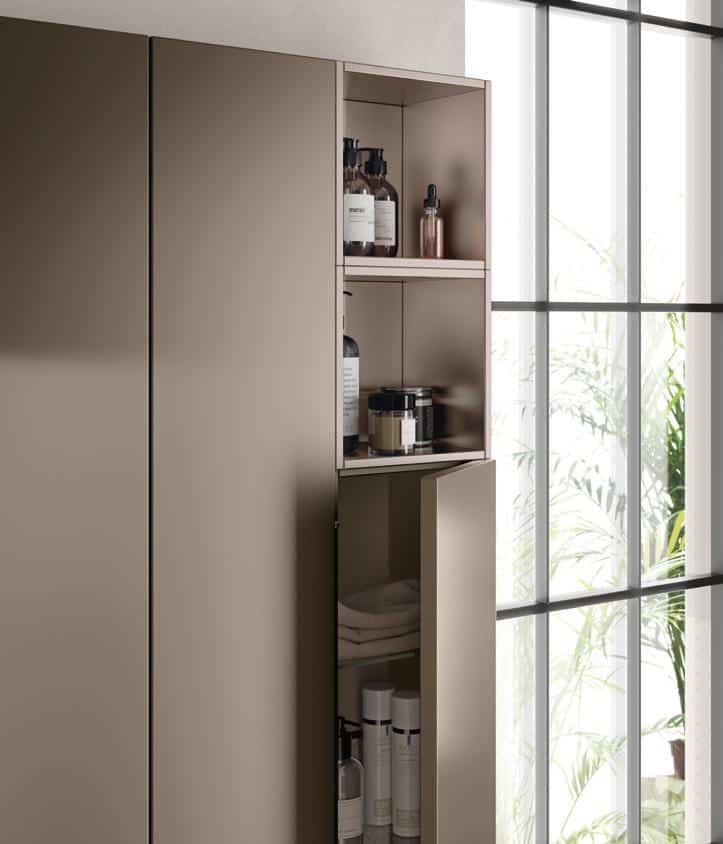 Modern bathroom cabinet with sleek design, open to reveal shelves with toiletries and towels, next to a large window with natural light.