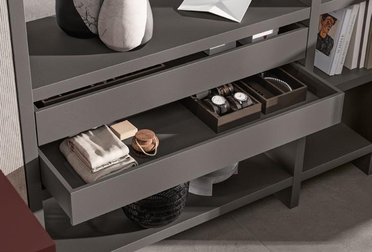 A modern shelf unit with decorative objects, books, watches in a tray, and neatly folded linens.