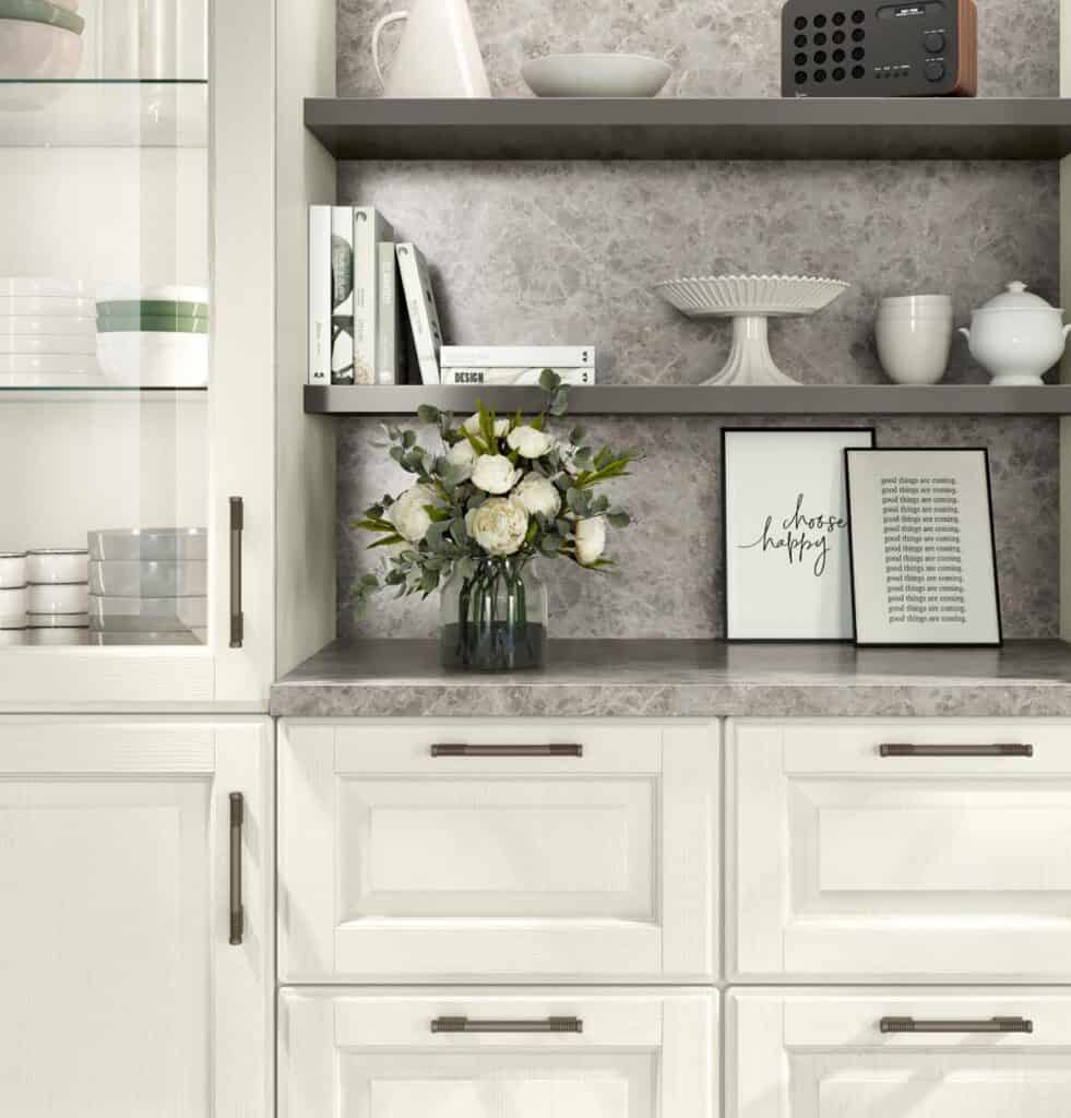 Kitchen shelf with decorative items, white cabinets, a vase of flowers, books, and framed inspirational quotes.