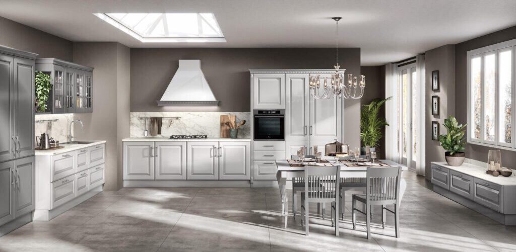 Modern kitchen with gray cabinetry, a marble countertop, central island with dining table, chandelier, and skylight.
