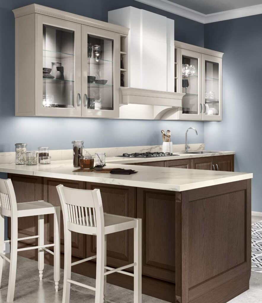 Modern kitchen with a marble island, white cabinets with glass doors, bar stools, and a built-in stovetop.