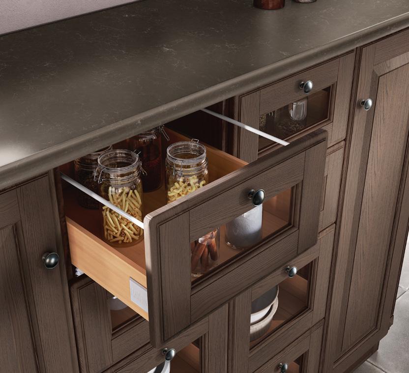 Wooden kitchen cabinet with an open drawer containing glass jars of pasta and other items.