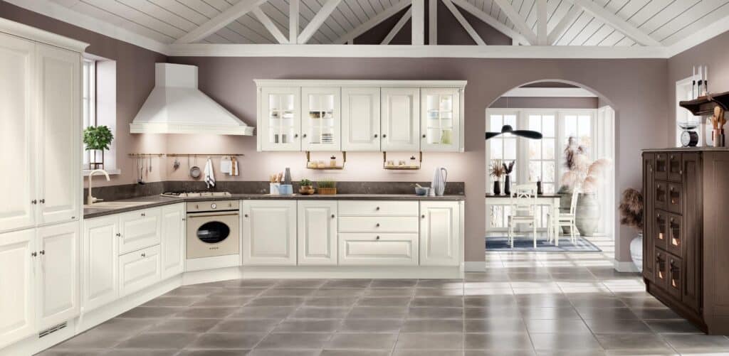 Spacious kitchen with cream cabinetry, dark countertops, a large oven, and a dining area with a round table and chairs by a window.