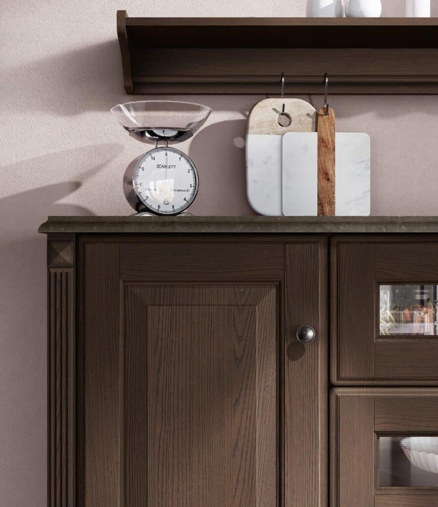 A dark wood kitchen cabinet with a scale and cutting boards on top.