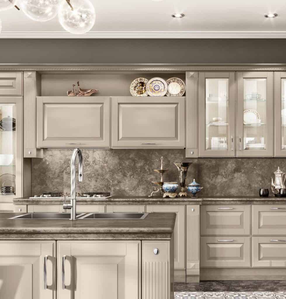 Elegant kitchen with beige cabinets, marble countertops, ornate dishware, and spherical pendant lights.