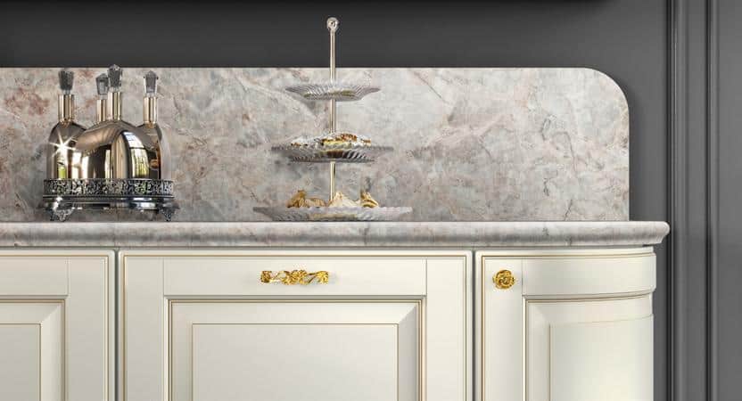 Elegant kitchen counter with a marble backsplash, silver canisters, and a tiered serving tray with pastries.