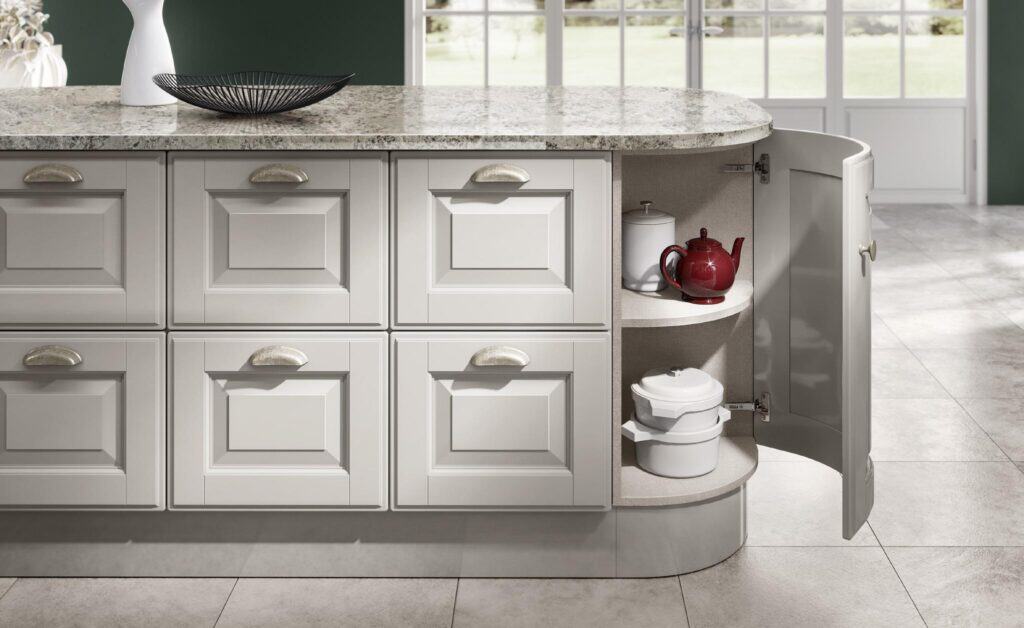 Kitchen island with white cabinets, open cupboard door revealing a red teapot, and white ceramic dishes inside.