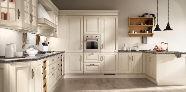 Elegant cream-colored kitchen with marble countertops, built-in oven, wooden shelves with kitchenware, and pendant lighting.