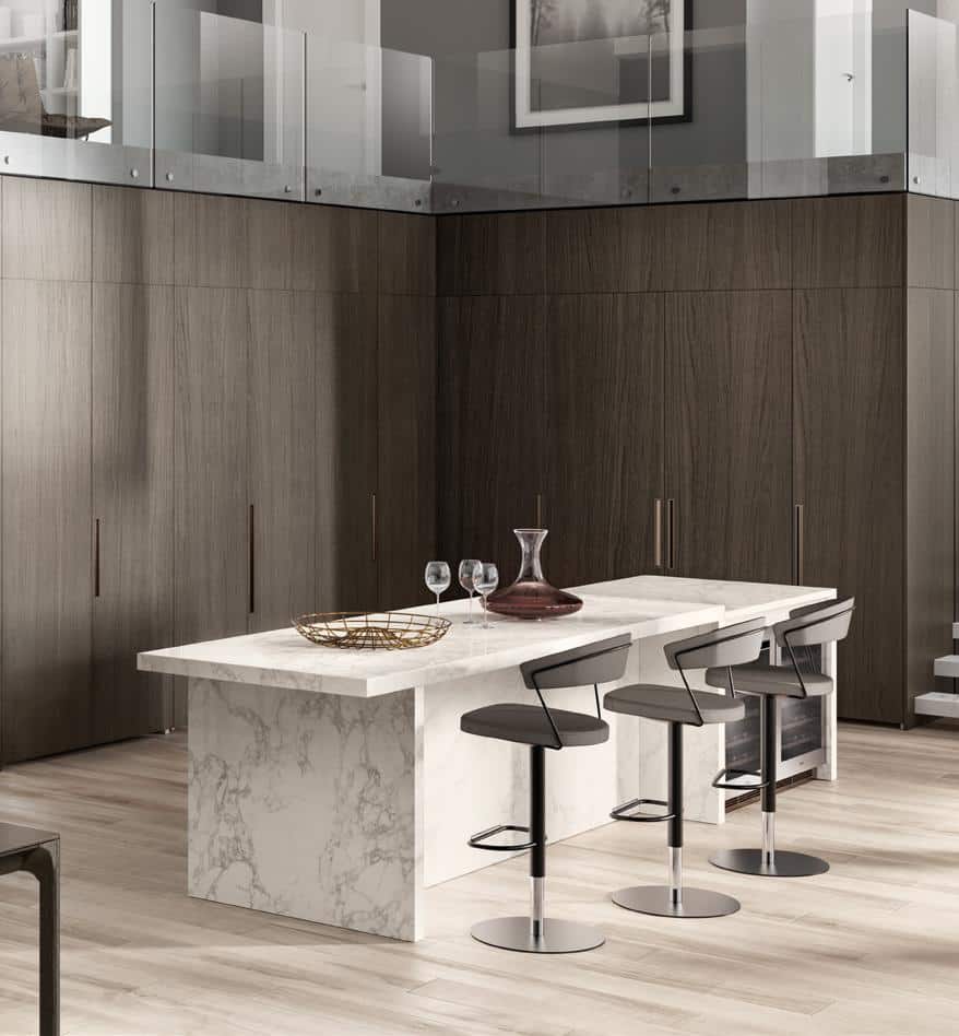 Modern kitchen with a marble island, three bar stools, wooden cabinetry, and glass railing.