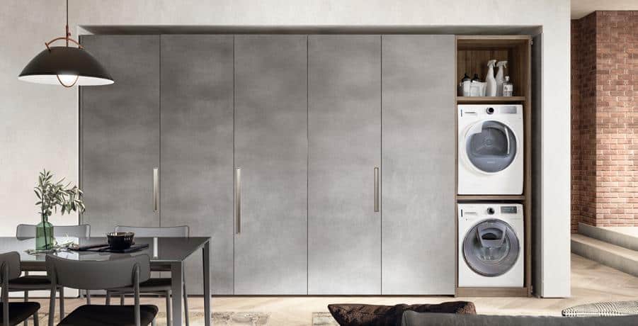 Modern interior with gray cabinetry, showcasing a built-in washing machine and dryer discreetly integrated into a hallway space next to a dining area.
