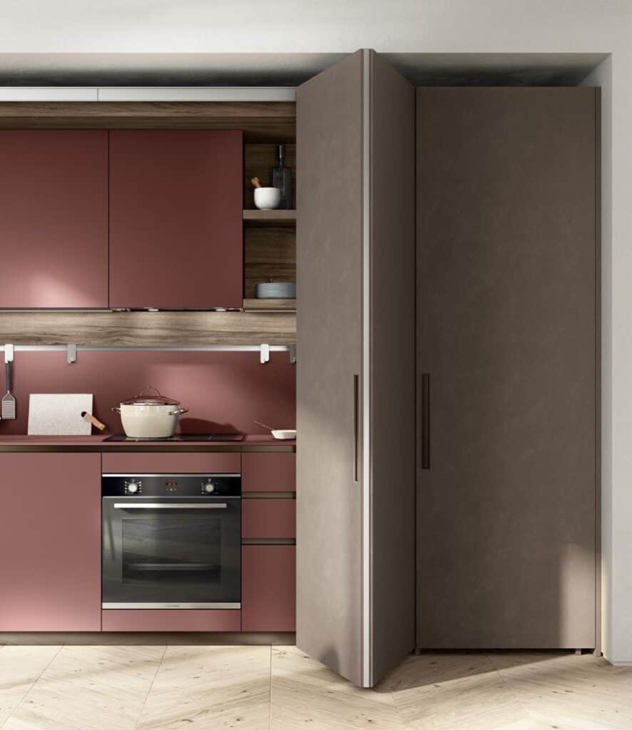 Modern kitchen with red and brown cabinetry, featuring an integrated oven and a stovetop with a pot.