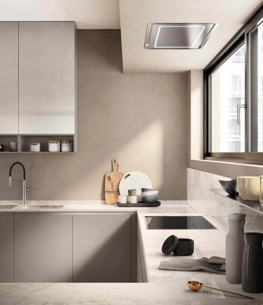 Modern kitchen with marble countertops, a sleek faucet, an induction cooktop, and minimalistic decor, featuring large windows and neutral tones.