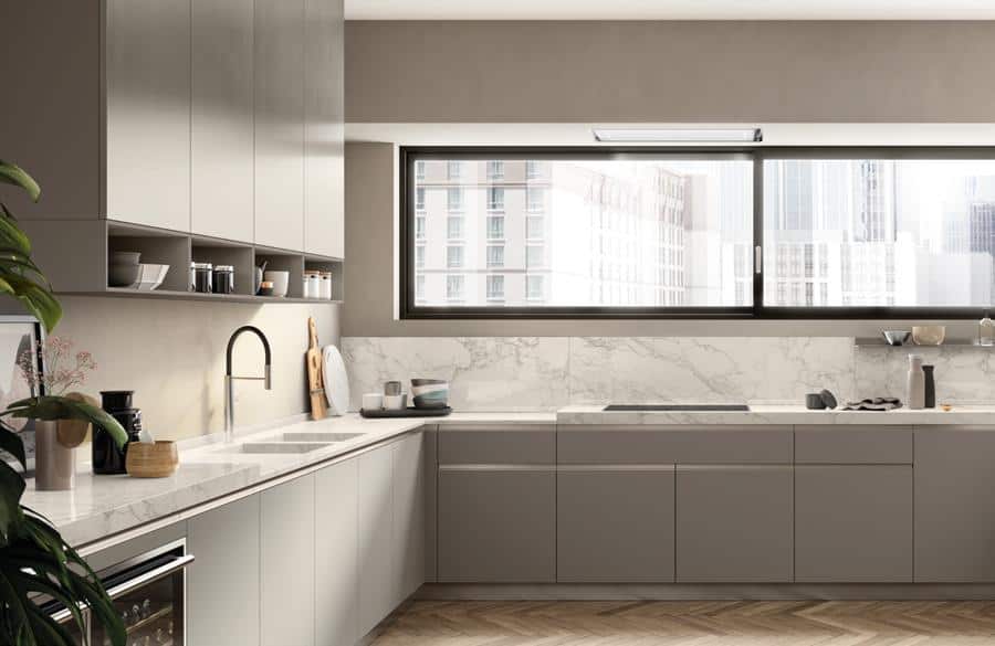 Modern kitchen with gray cabinets, marble countertops, and a large window overlooking city buildings.